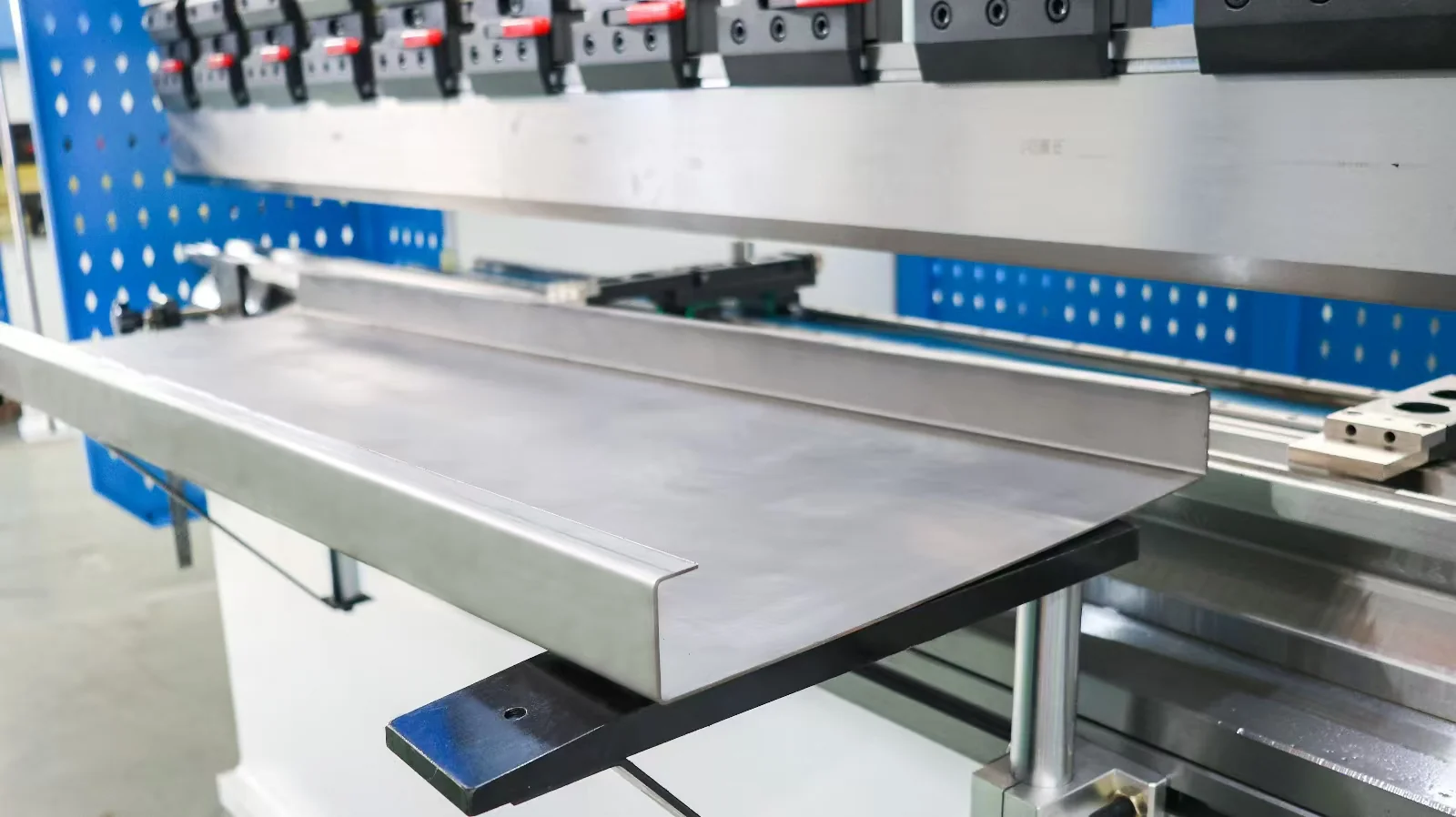Formed sheet-metal channel resting on the front supports of a press brake.