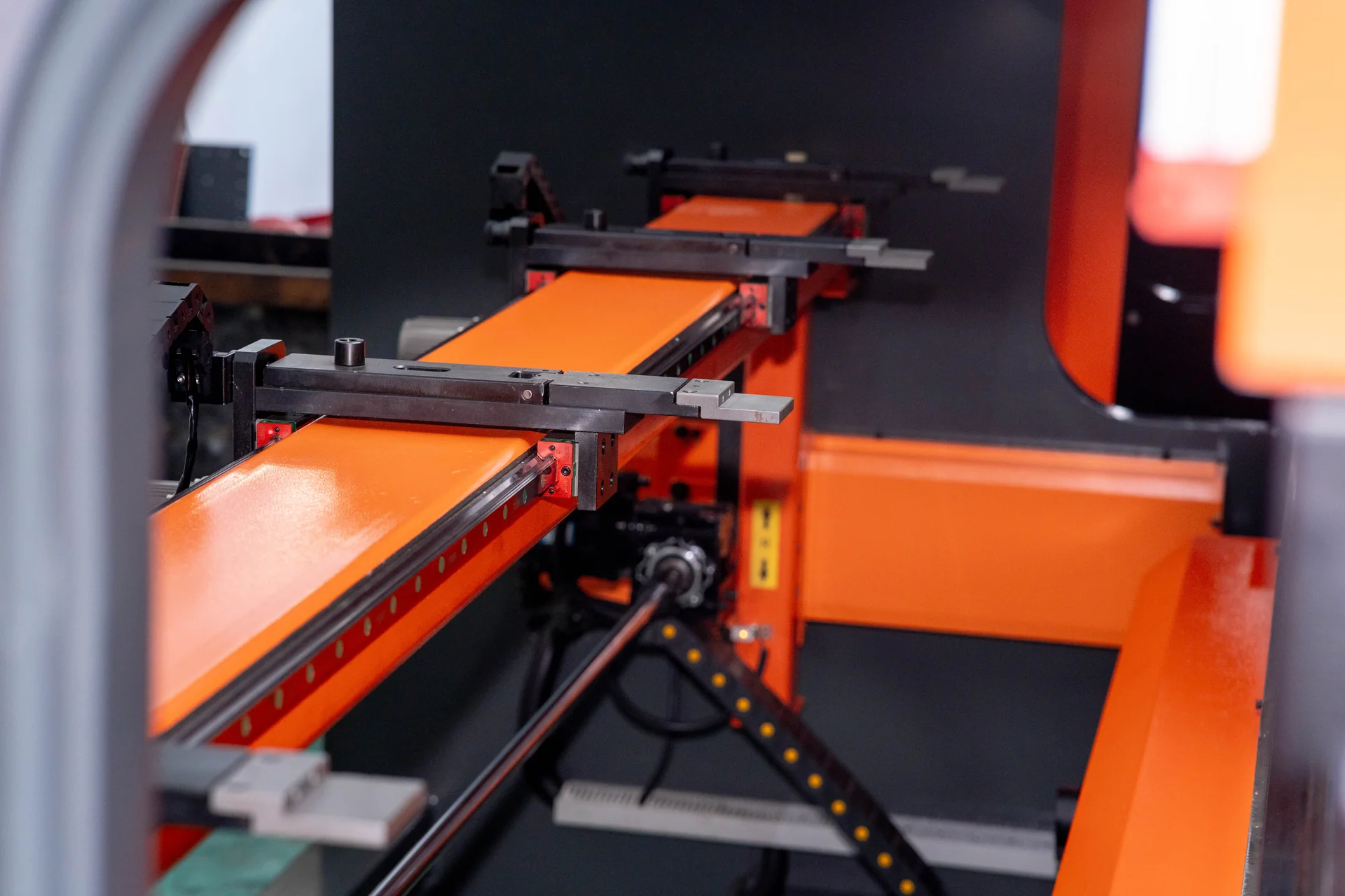 Backgauge beam, guide rails and positioning fingers inside a CNC press brake.