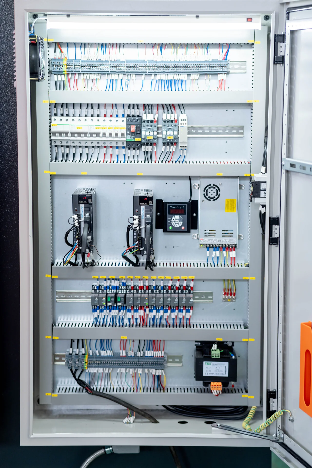 Open electrical cabinet showing labeled wiring and drives on a CNC press brake.