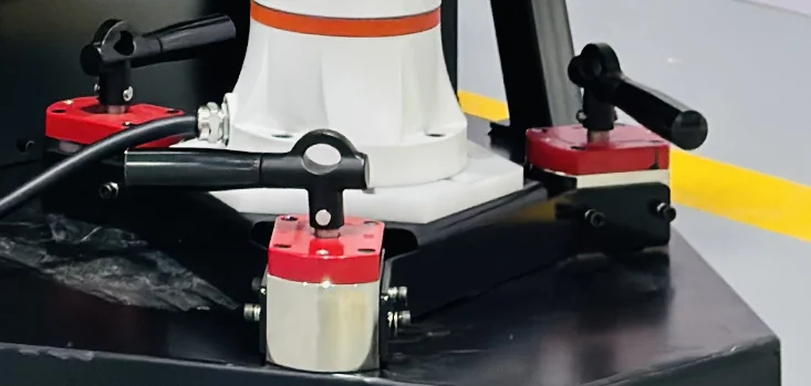 Robot base secured by a triangular bracket with three lever-operated magnetic mounts.