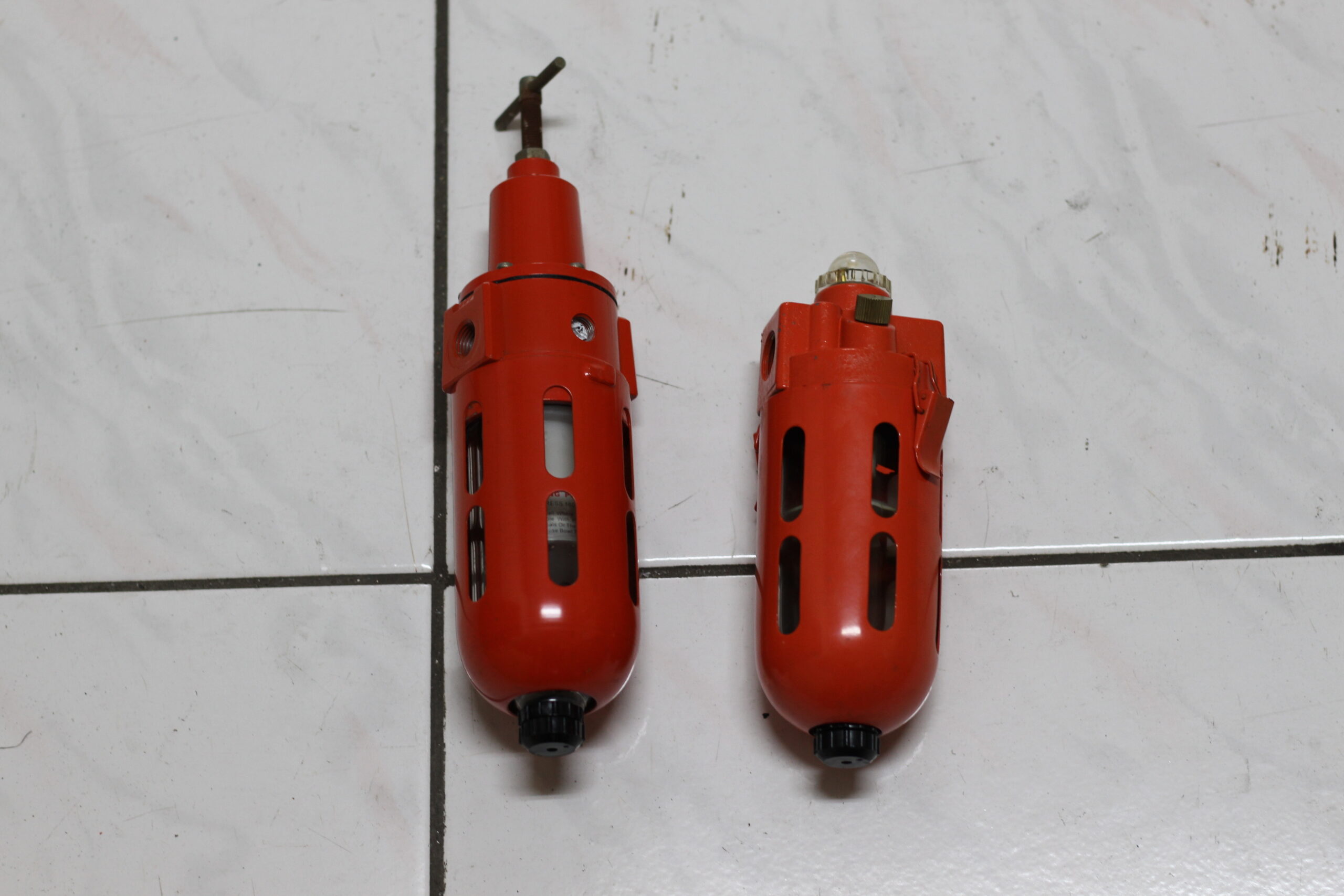 Two red compressed-air filter and pressure-regulator components