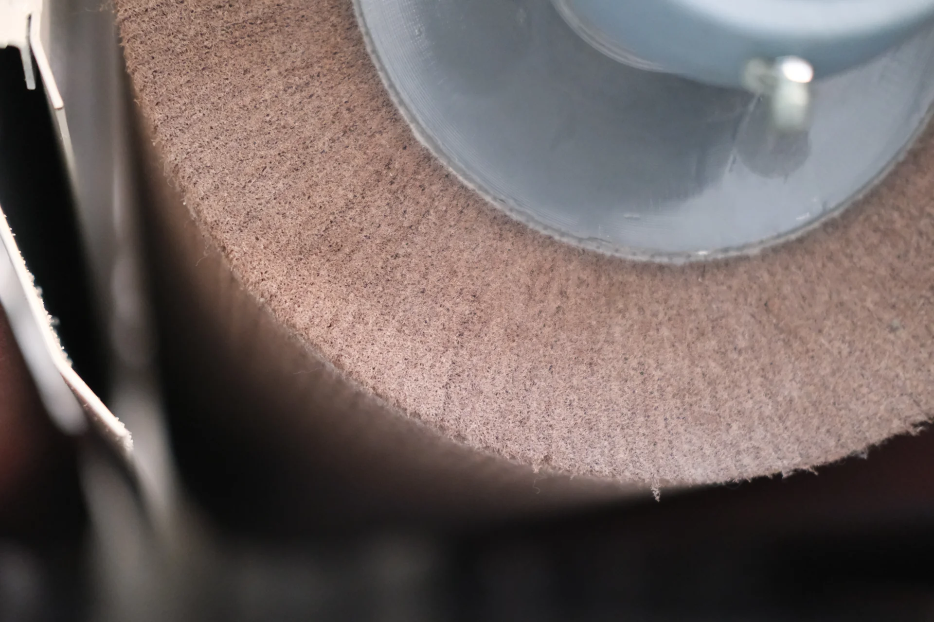 Close-up of a brown fibrous abrasive wheel and part of its metal hub.