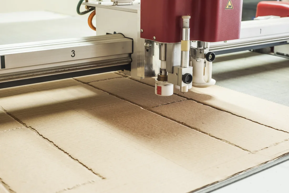 Corrugated board being cut into packaging shapes