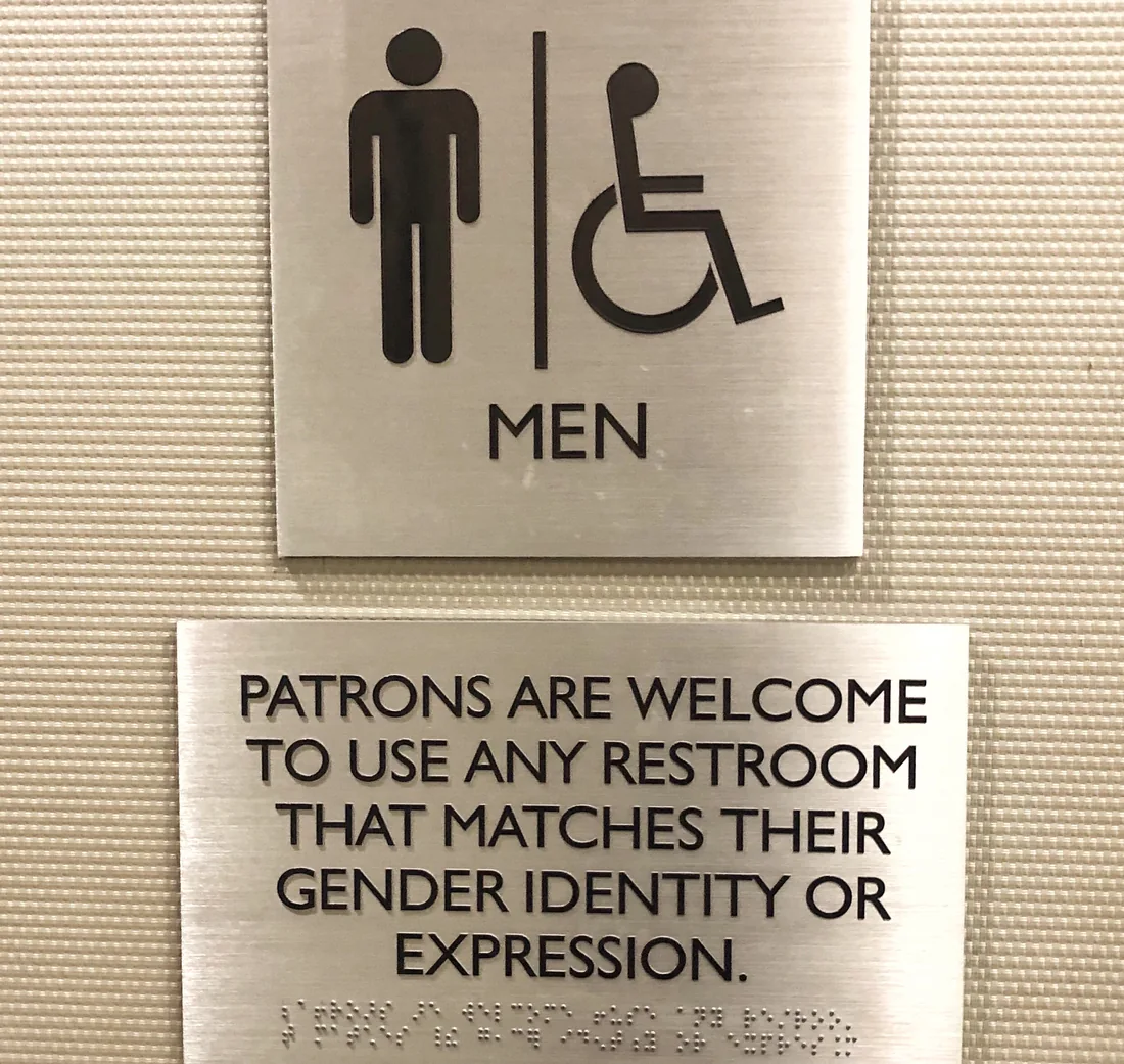 Metal wayfinding signs with accessible restroom symbols