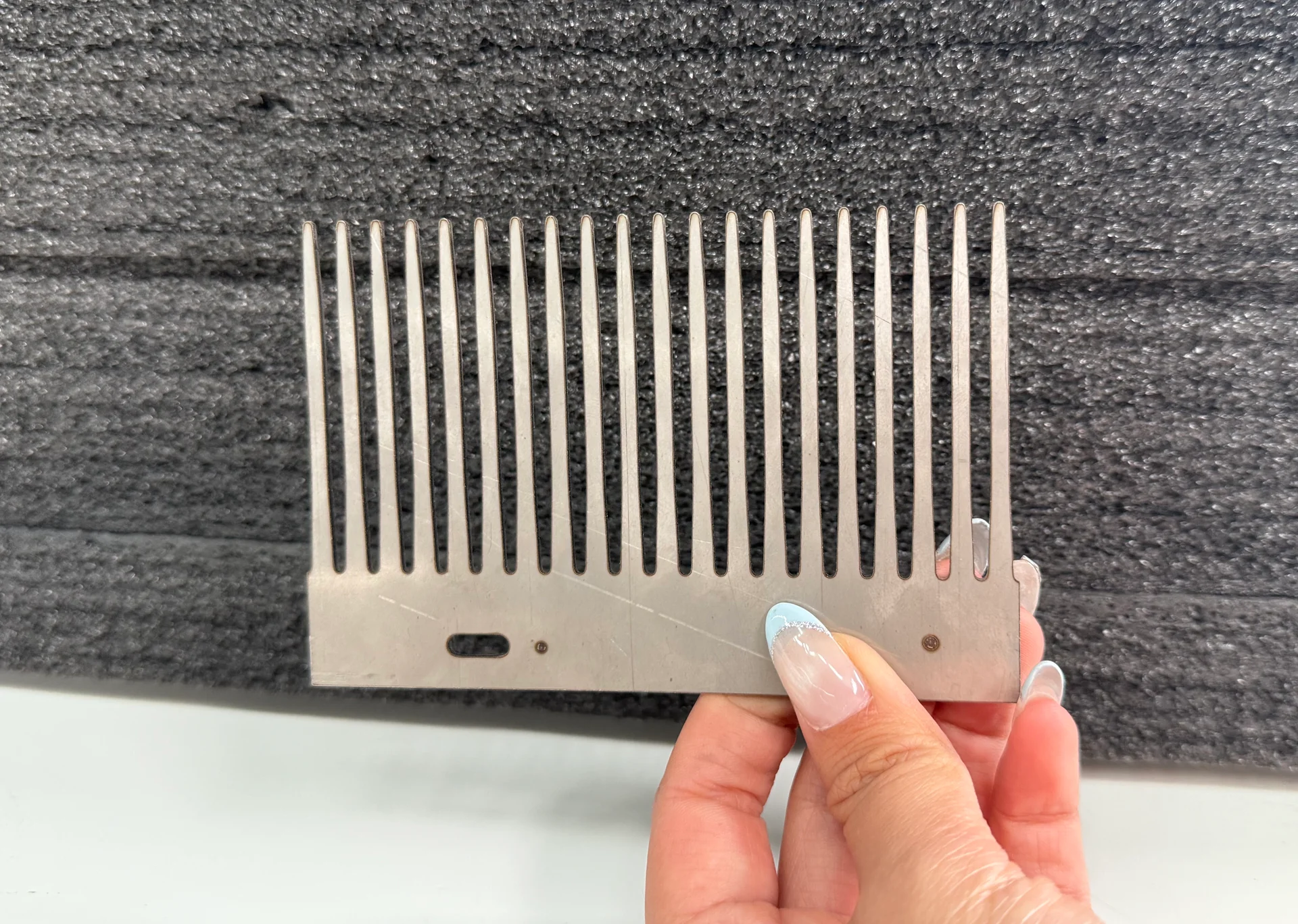 Hand-held metal cutting sample with a row of long narrow slots