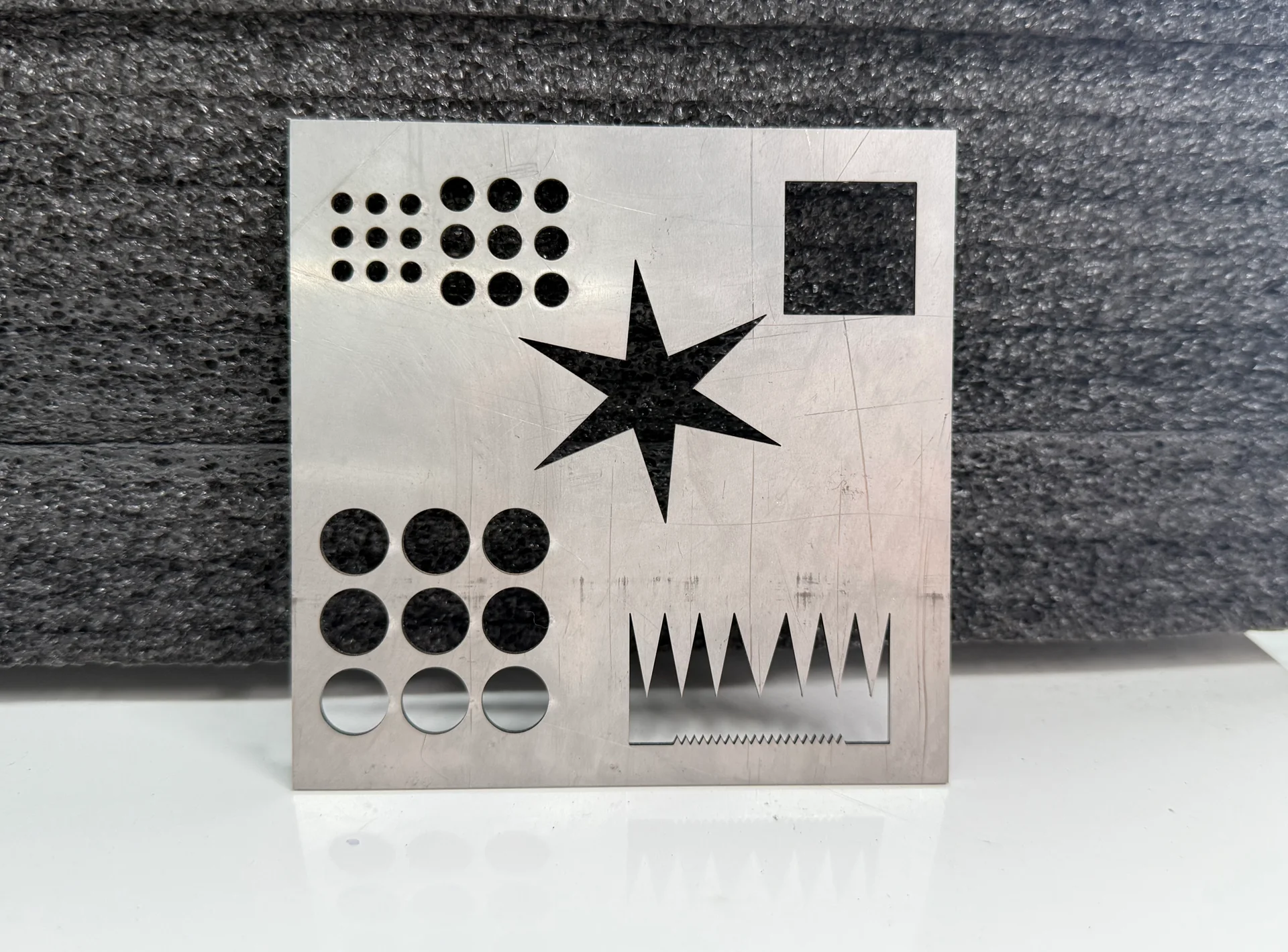 Metal acceptance-style sample with geometric cut features