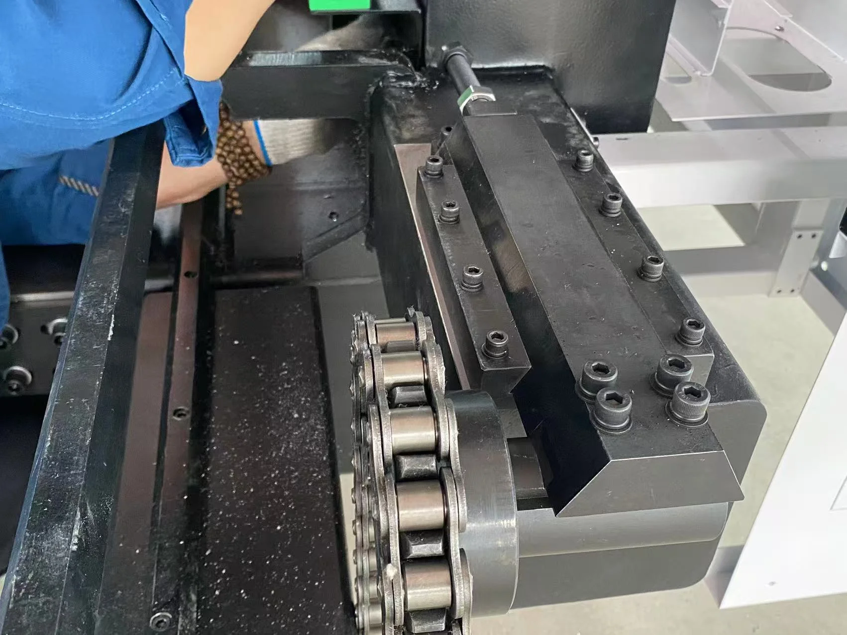 Close-up of a roller chain and bolted mechanism on a laser machine exchange-table assembly