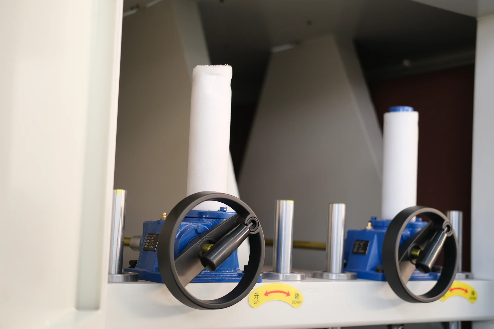 Two manual adjustment handwheels with blue gearboxes and vertical screw assemblies.