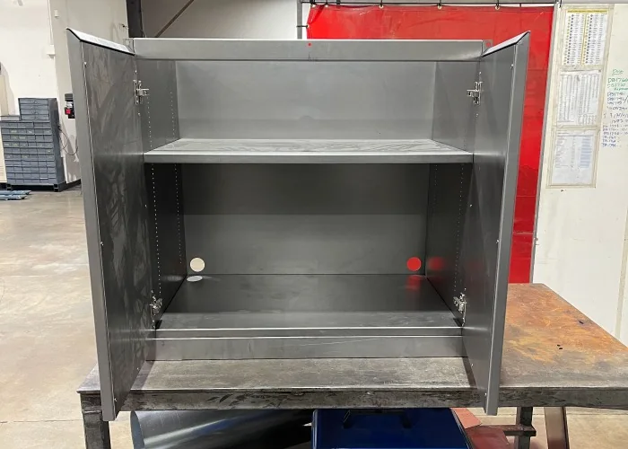 Uncoated sheet metal cabinet showing hinges, folded edges and mounting holes; application reference