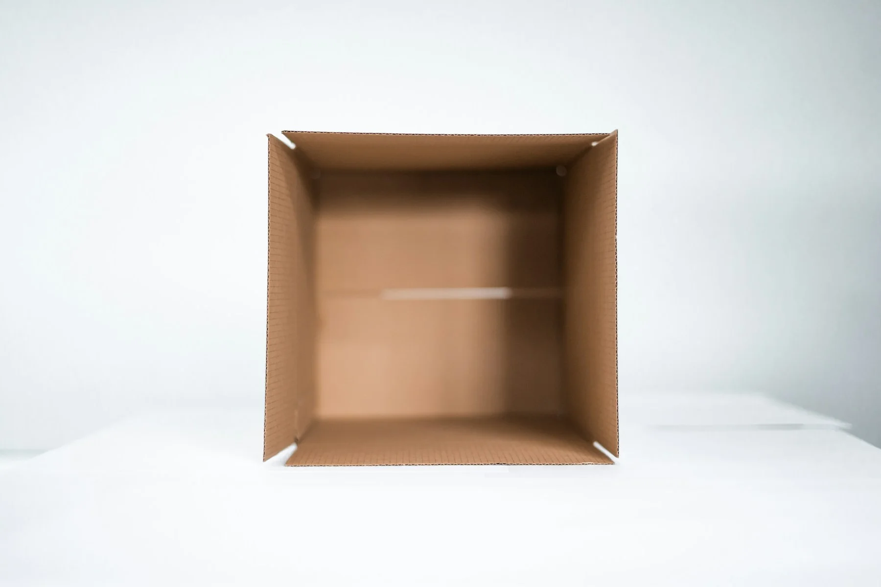 Open folded cardboard box showing its interior and corner structure; packaging illustration