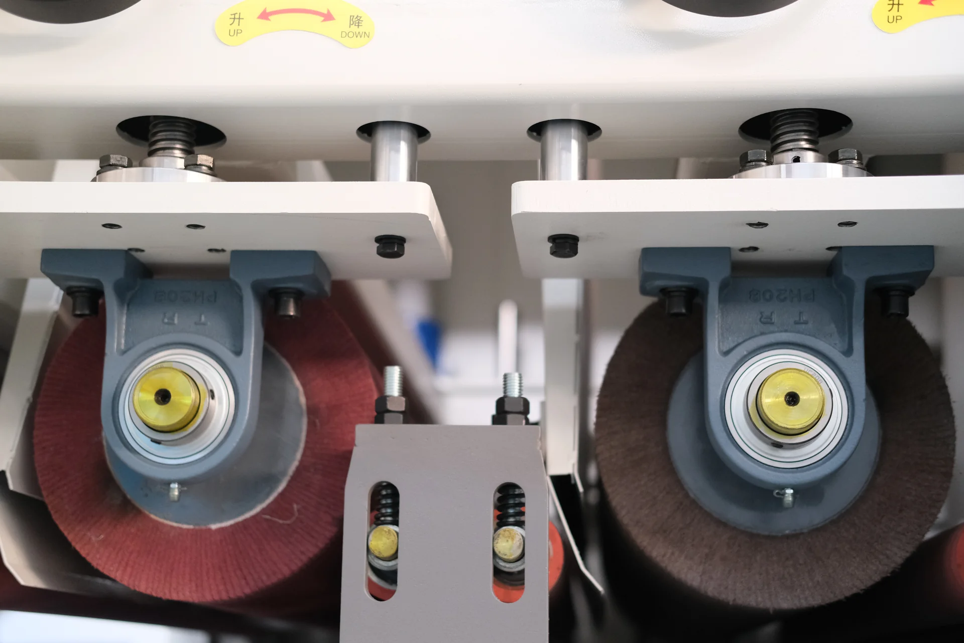 Paired abrasive wheels with bearing housings, adjustment screws and spring-loaded supports.