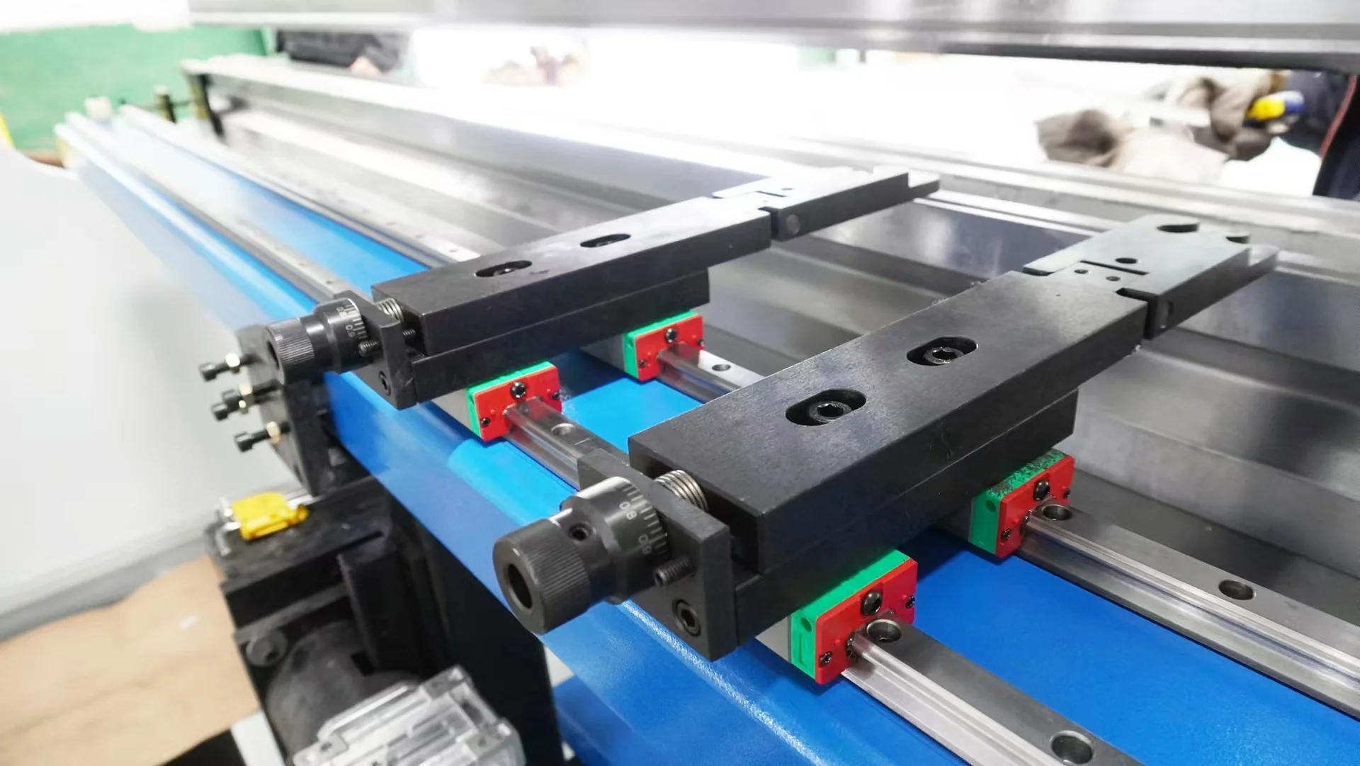Two press brake backgauge fingers with adjustment dials on a linear rail.