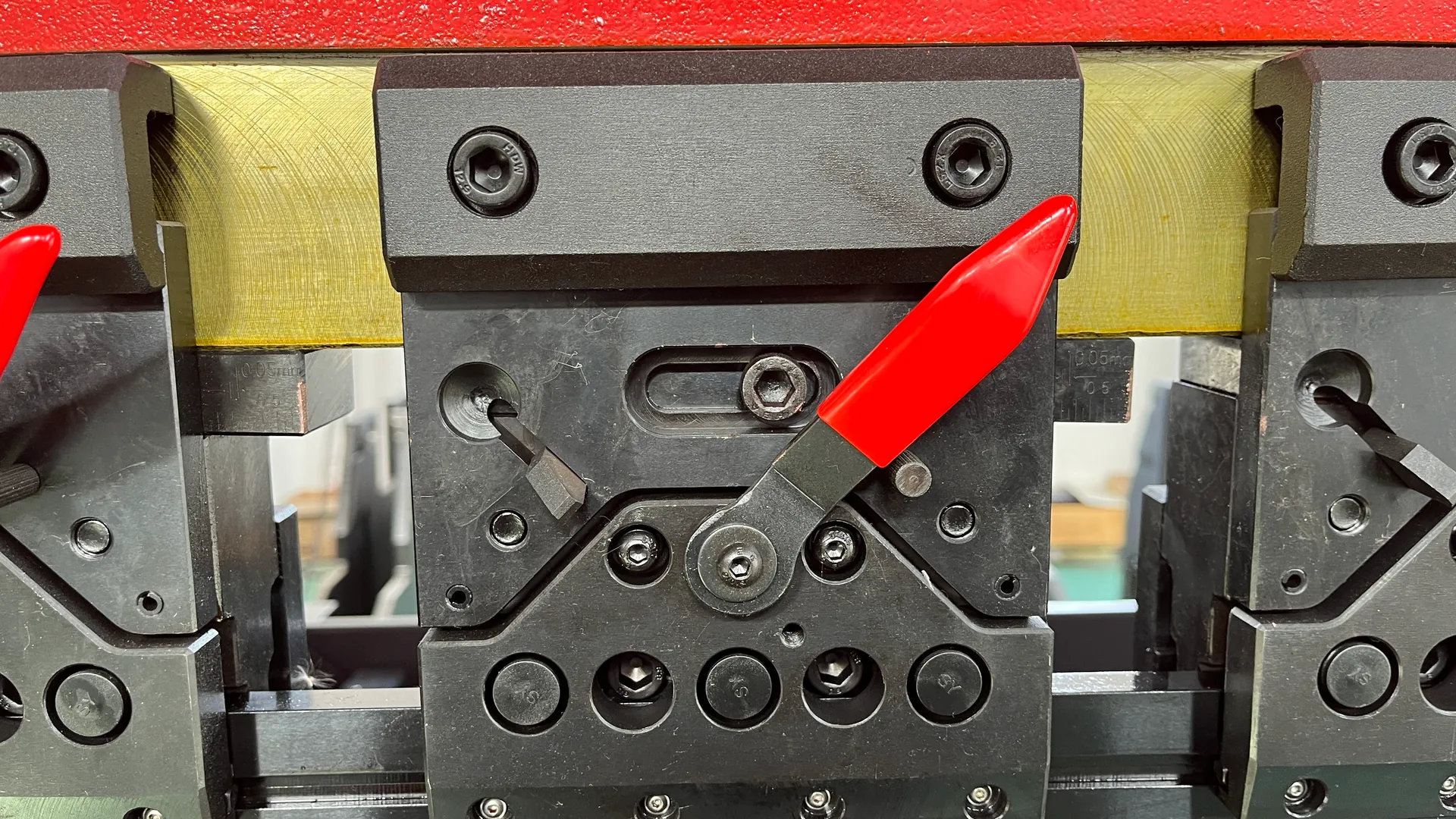 Segmented press brake tooling held by a clamp with a red release lever.