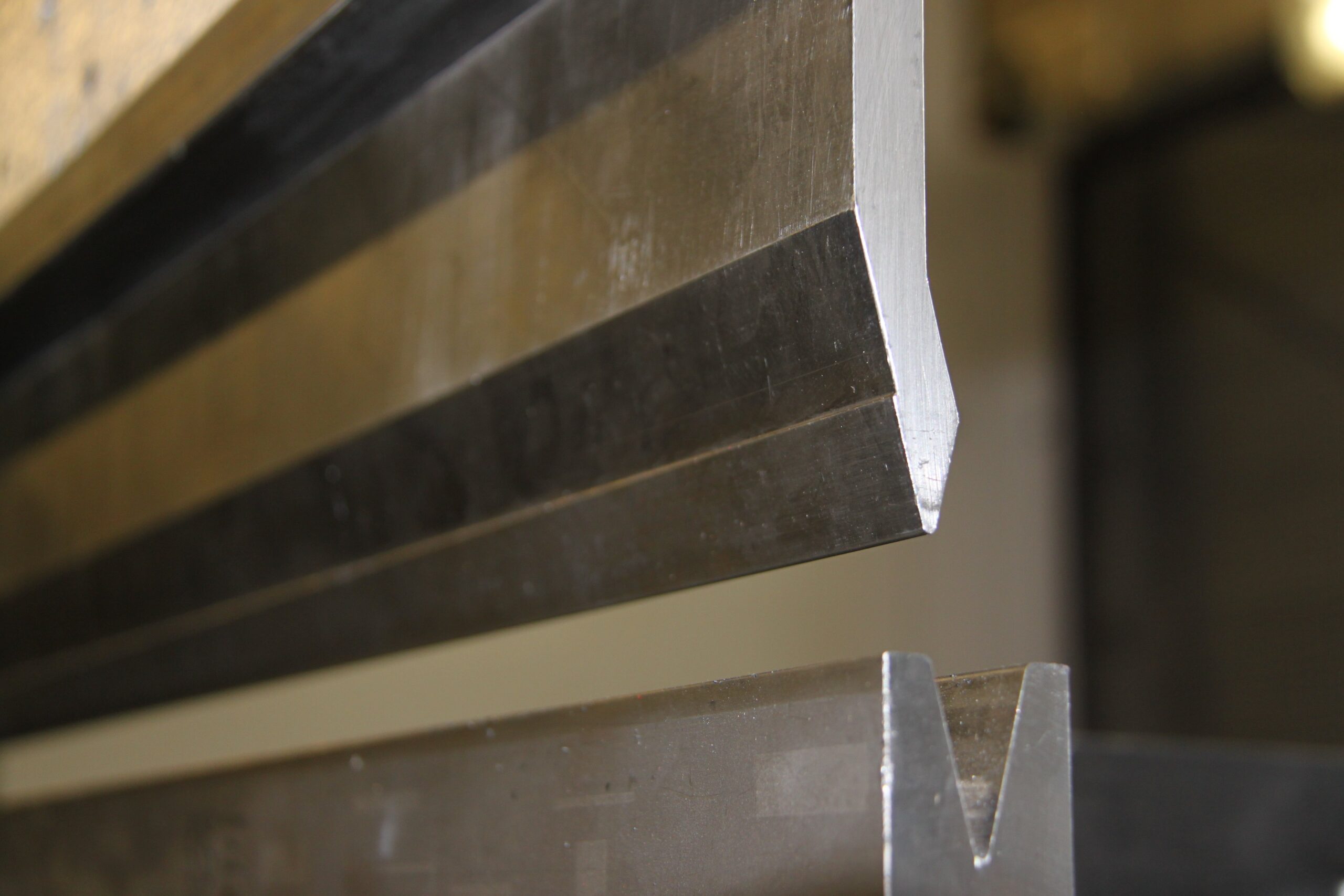 Close-up photograph of press brake punch and V-die tooling