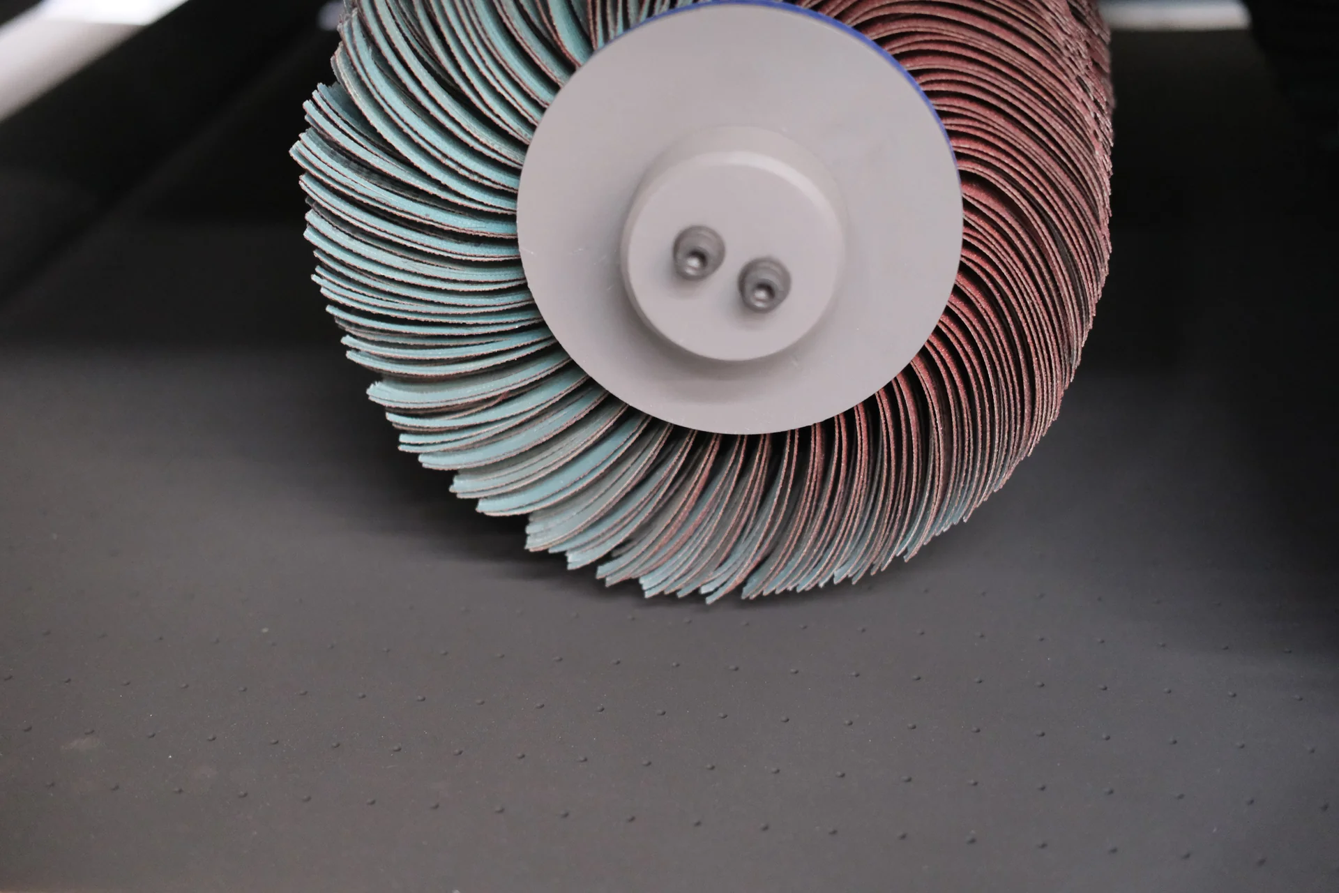 Close view of alternating red and green abrasive flaps around a brush hub.