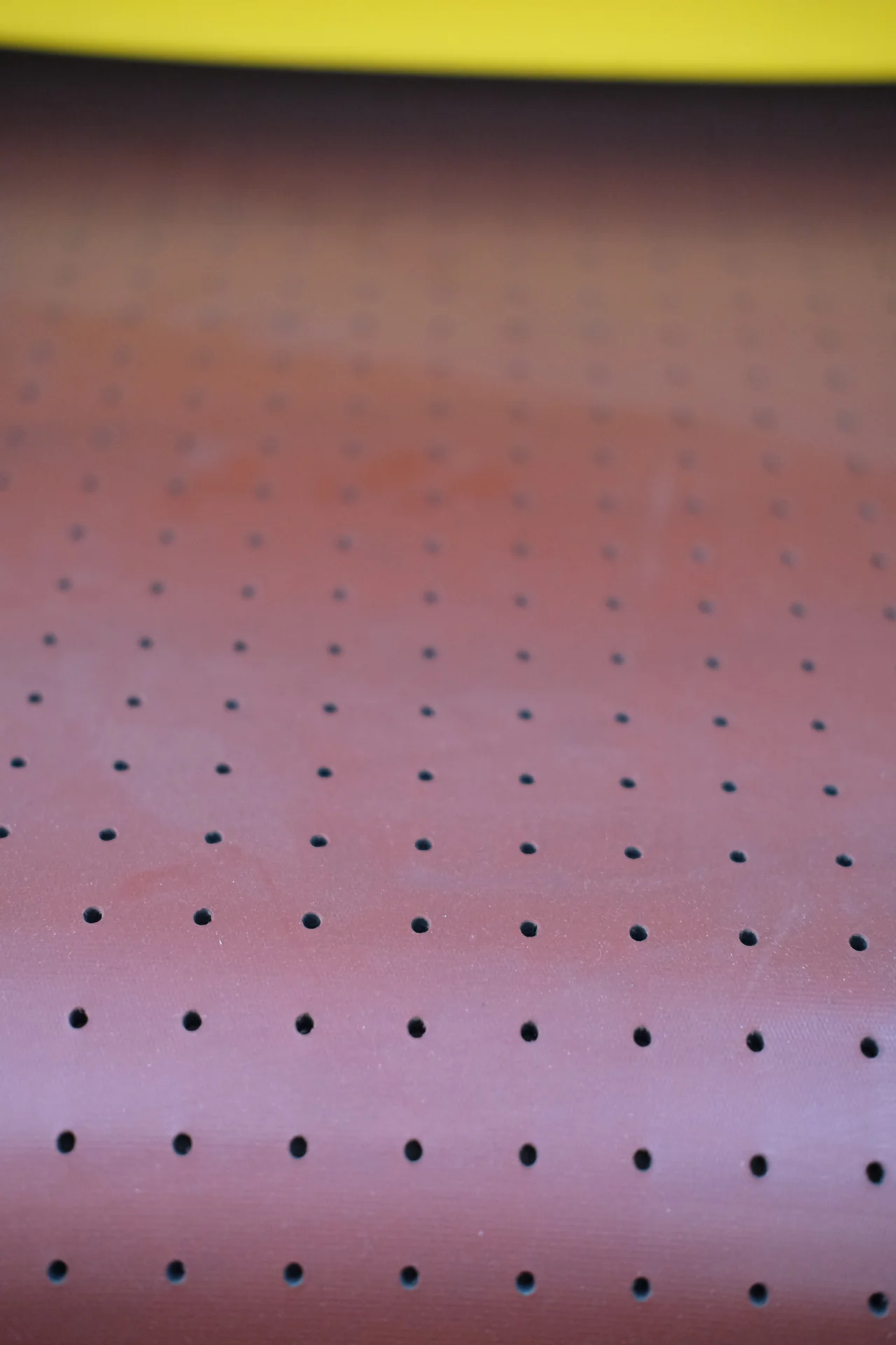 Close-up of a red perforated conveyor belt surface.
