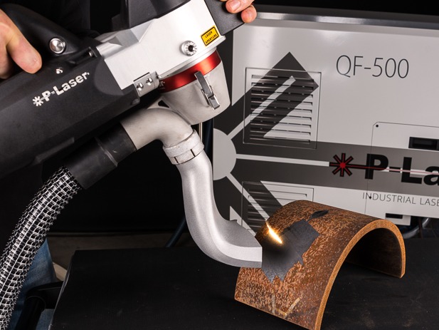 P-Laser removes rust from a curved steel sample, revealing a cleaned patch beside the extraction nozzle
