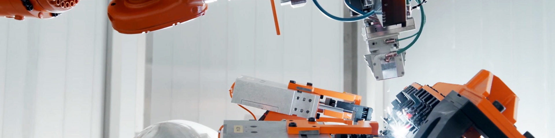 Industrial robot laser welding an automotive door assembly inside a white enclosed workcell