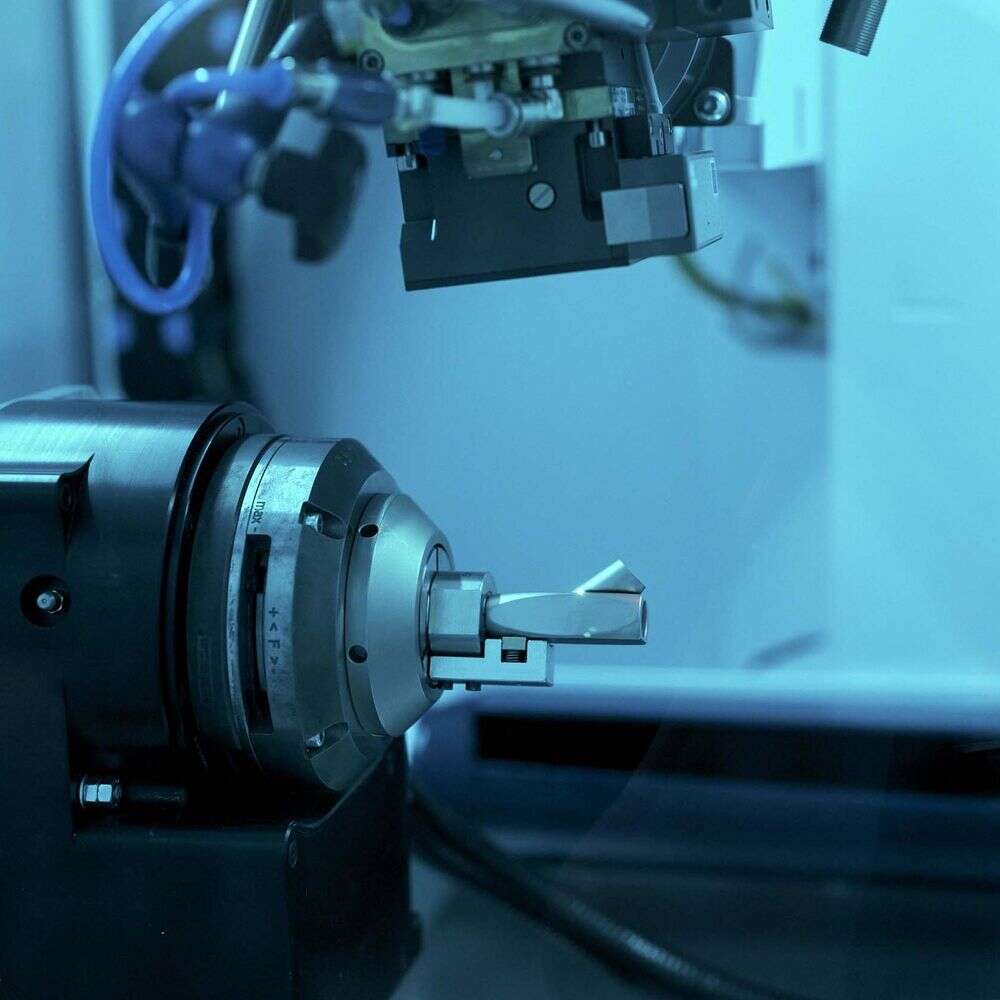 Fixed laser processing head above a rotary chuck holding an endoscope eyepiece at Karl Storz