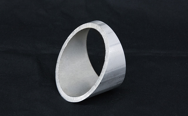 Third-party photograph of an angled-cut metal tube ring with its cut edge visible against a dark background