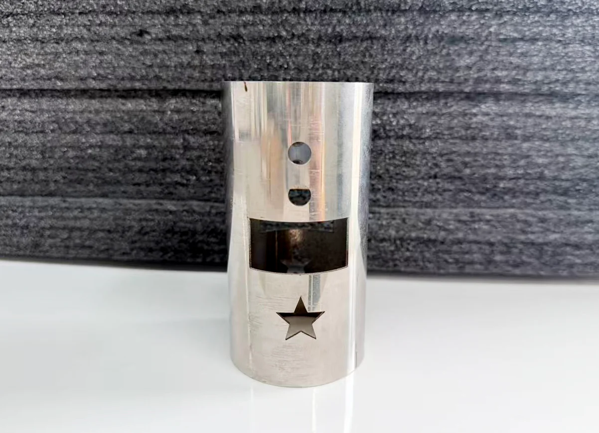 Round metal tube sample with circular holes, a rectangular window and a star-shaped opening